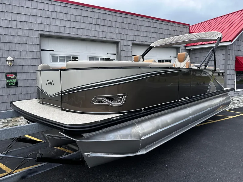 Slide: The Image of 2025 Avalon 2385 LSZ Quad Lounger Tri Toon, high-performance pontoon boat in driveway. - 1