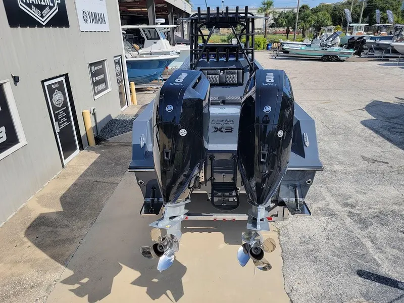 Slide: The Image of 2026 Shallow Sport 32 X3 boat with dual outboard engines, parked outdoors. - 6