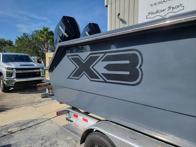 Slide: The Image of 2026 Shallow Sport 32 X3 boat on trailer, parked near a truck. - 9