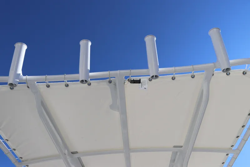 Slide: The Image of Robalo R200 Center Console 2025 boat canopy with rod holders against blue sky. - 17