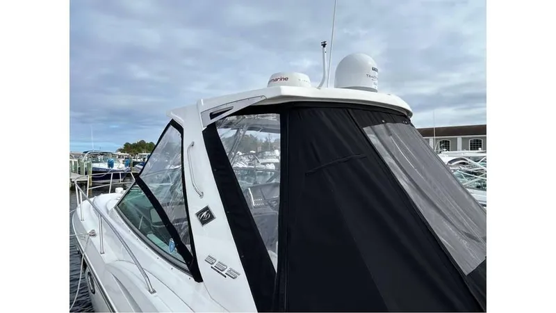 Slide: The Image of 2021 Monterey 335 Sport Yacht with black canopy, docked under cloudy skies. - 2