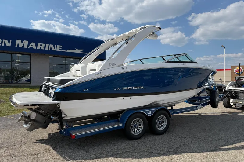 Slide: The Image of 2025 Regal LS6 boat on trailer, displayed outside marine dealership under blue sky. - 14