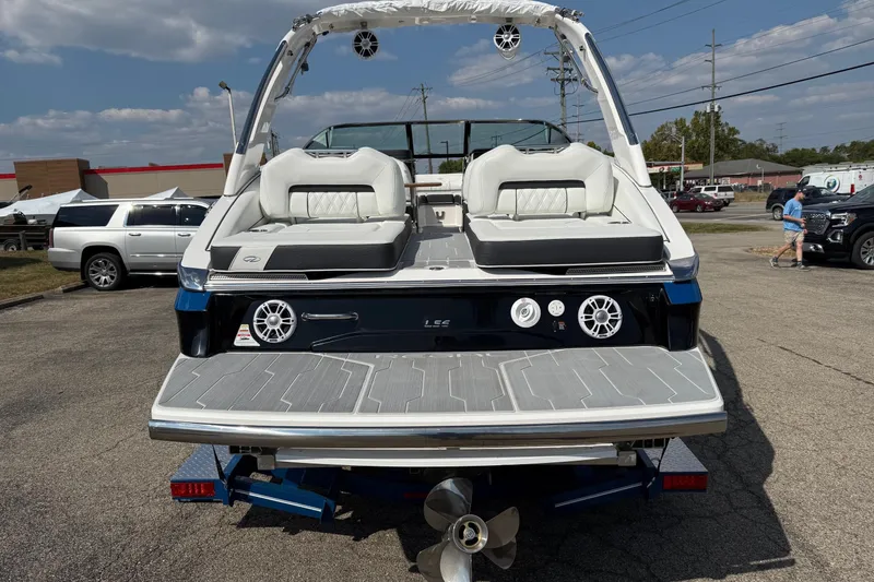 Slide: The Image of 2025 Regal LS6 boat rear view with seating and speakers, parked outdoors. - 15
