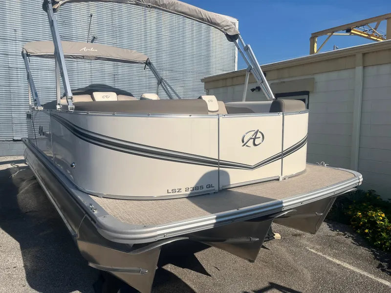 Slide: The Image of 2024 Avalon 2385 LSZ Quad Lounger pontoon boat, beige exterior, docked outdoors. - 2
