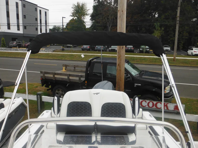 Slide: The Image of 2025 Tidewater 198 CC Adventure boat with bimini top, parked near a road. - 46