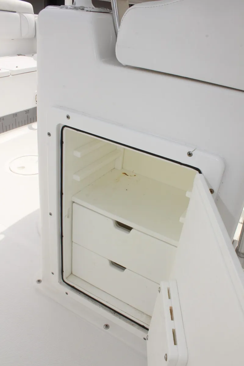 Slide: The Image of 2015 Sea Hunt Ultra 235 SE boat storage compartment with open door and drawers. - 26