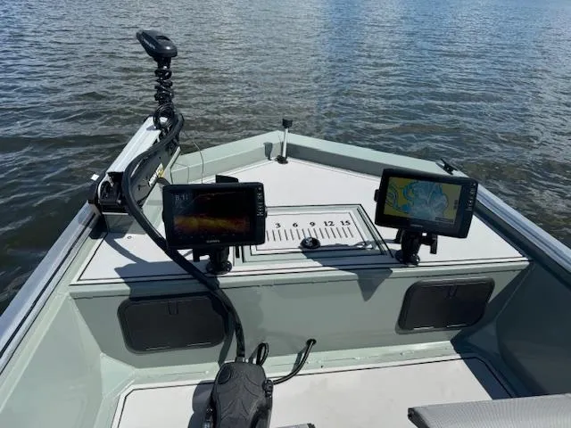 Slide: The Image of Custom Ultimate Panfish XL 2025 boat with dual fish finders on a calm lake. - 16