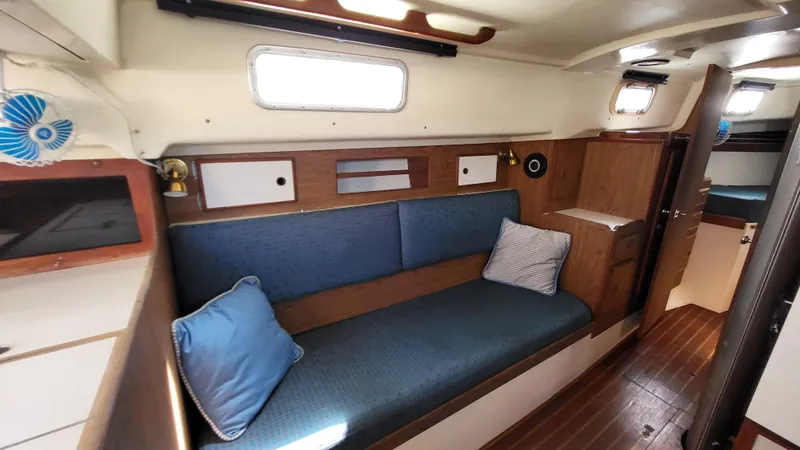 Slide: The Image of 1979 Pearson 365 Sloop interior with blue cushions and wooden accents. - 19