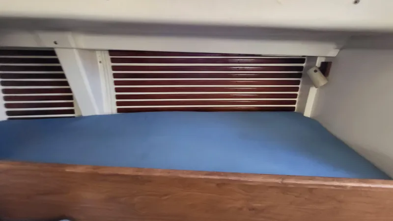 Slide: The Image of 1979 Pearson 365 Sloop interior cabin with blue cushion and wooden accents. - 23