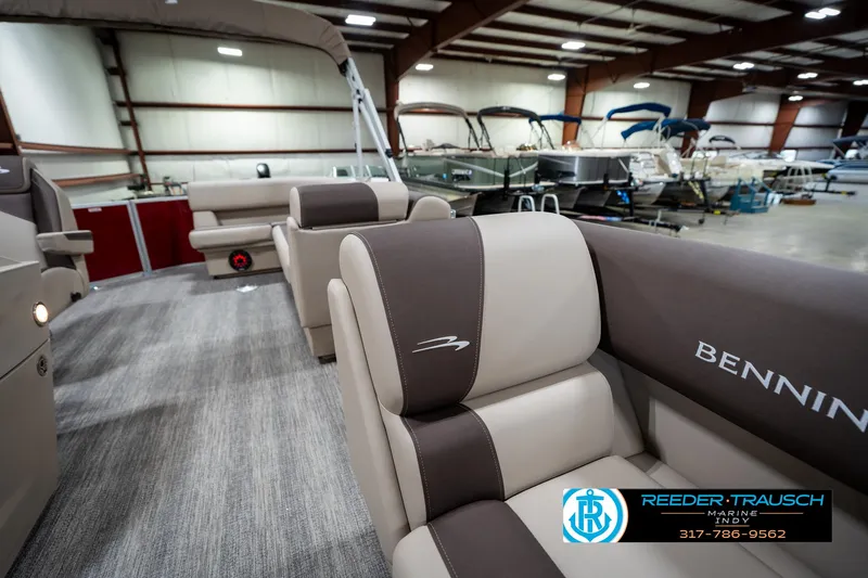 Slide: The Image of 2025 Bennington 21 SLS pontoon boat interior with plush seating in a showroom. - 19