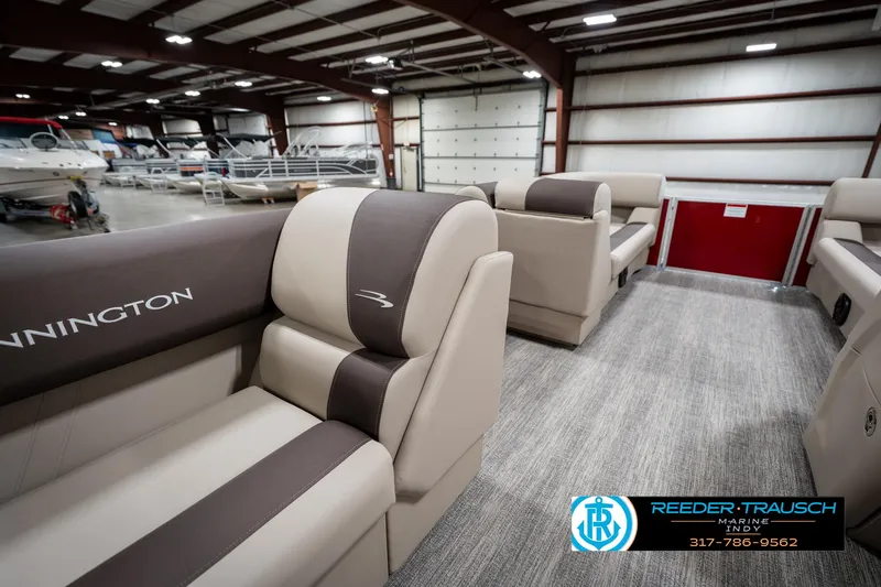Slide: The Image of 2025 Bennington 21 SLS pontoon boat interior with beige and brown seating in a showroom. - 25