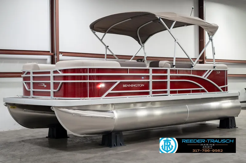 Slide: The Image of 2025 Bennington 21 SLS pontoon boat with red exterior and canopy in showroom. - 3