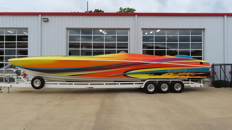 The Image of Colorful 2001 Outerlimits 42 Legacy speedboat on trailer, parked outside a garage. - 0
