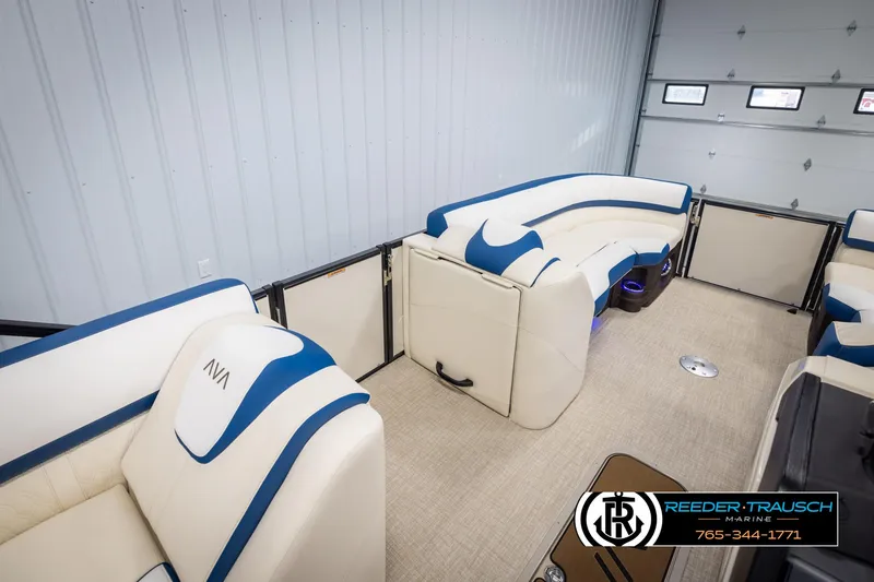 Slide: The Image of 2025 Avalon Catalina VRB boat interior with white and blue seating, displayed in a showroom. - 21