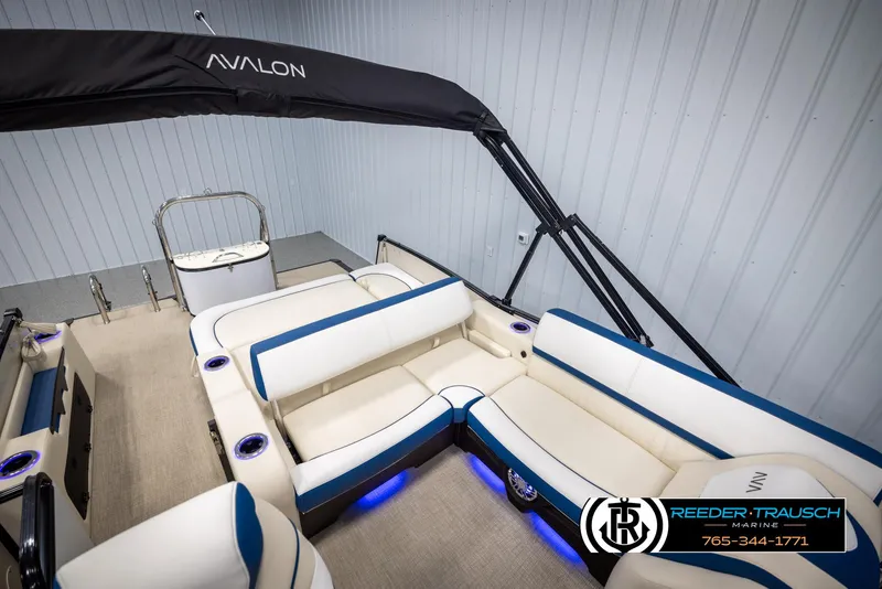 Slide: The Image of 2025 Avalon Catalina VRB boat interior with white and blue seating, under soft lighting. - 24