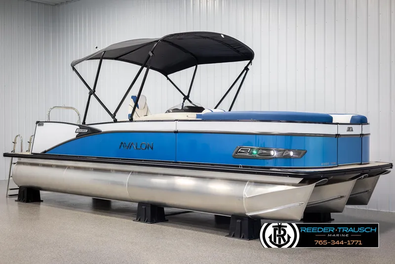 Slide: The Image of 2025 Avalon Catalina VRB pontoon boat with blue accents and canopy in showroom. - 3