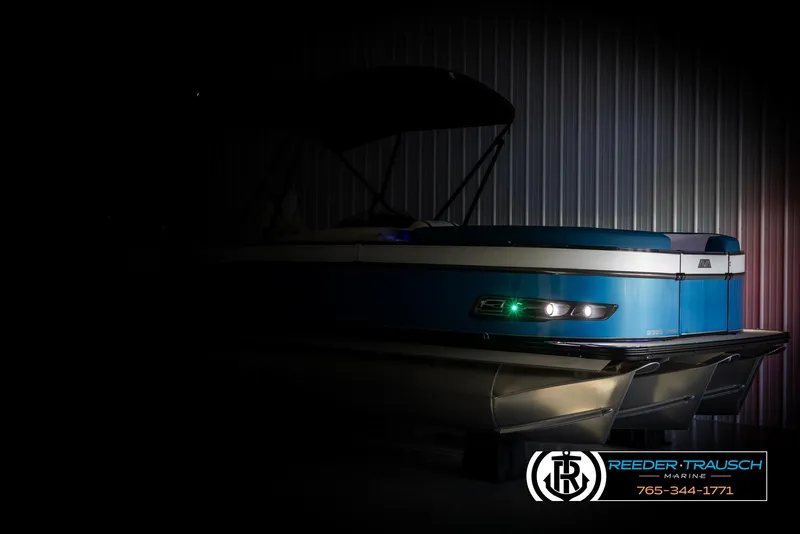 Slide: The Image of 2025 Avalon Catalina VRB pontoon boat in dimly lit showroom, Reeder-Trausch Marine branding visible. - 4
