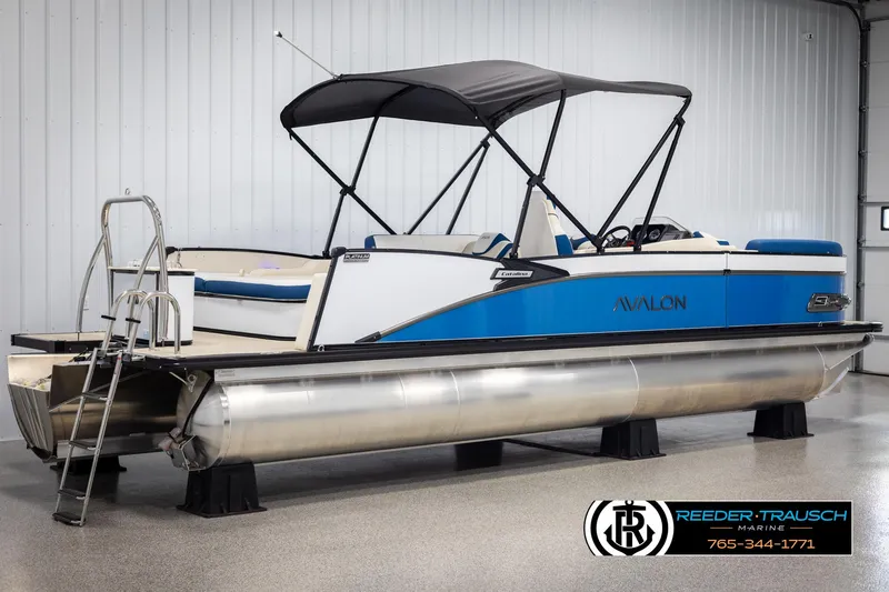 Slide: The Image of 2025 Avalon Catalina VRB pontoon boat with blue accents and canopy in showroom. - 6