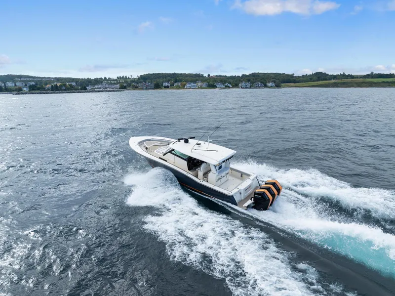 Slide: The Image of 2023 Scout 425 LXF boat cruising on open water, scenic coastal background. - 12