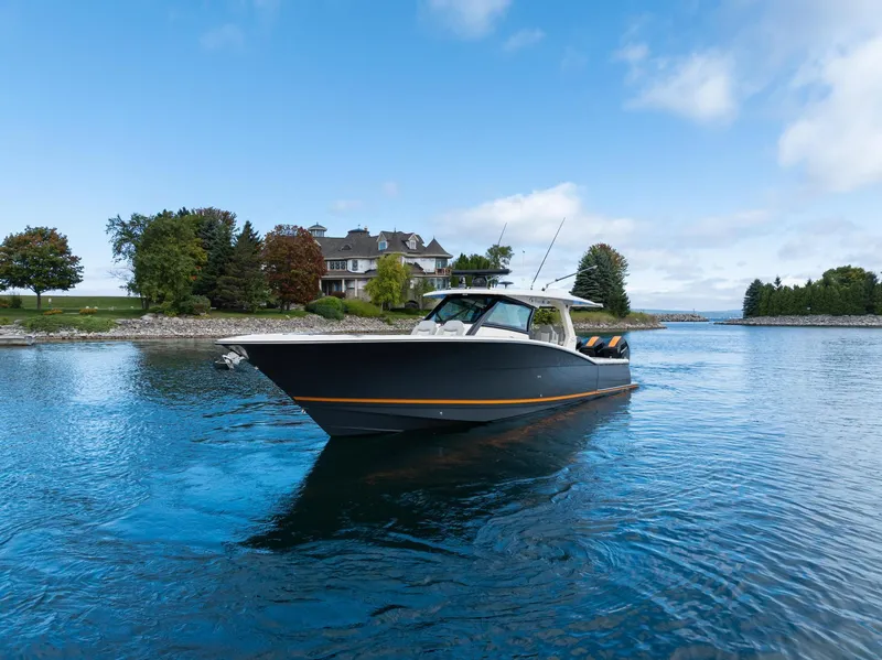 Slide: The Image of 2023 Scout 425 LXF boat cruising on a serene lake near a picturesque shoreline. - 16