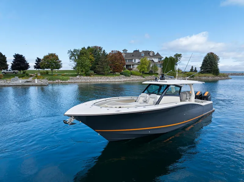 Slide: The Image of 2023 Scout 425 LXF boat on serene lake near elegant waterfront home. - 17