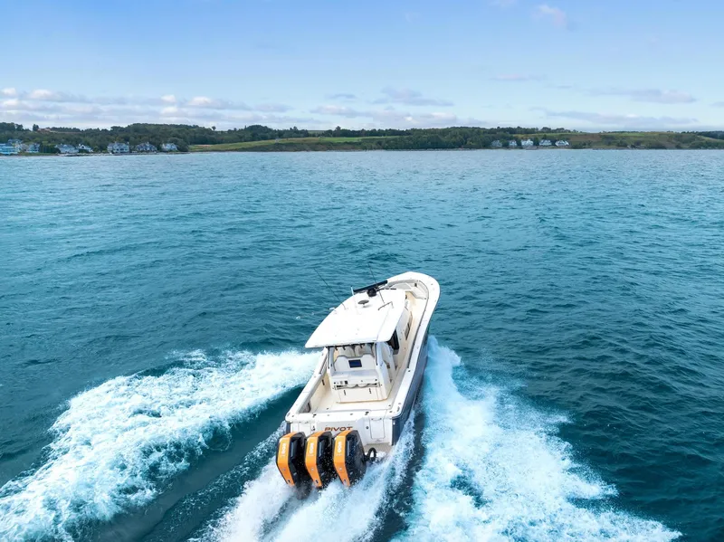 Slide: The Image of 2023 Scout 425 LXF boat cruising on open water with scenic coastline. - 2