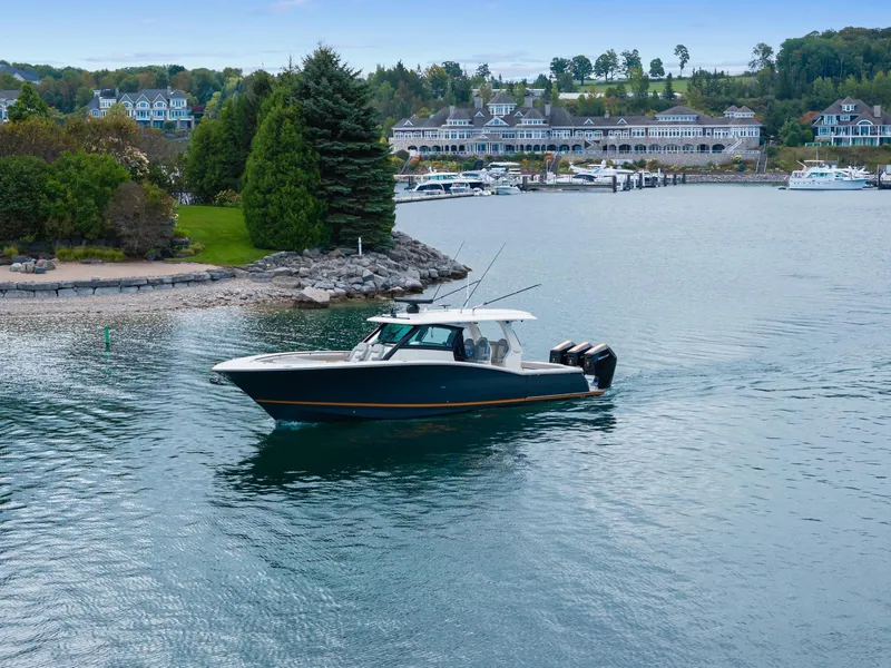 Slide: The Image of 2023 Scout 425 LXF boat cruising near a scenic waterfront with lush greenery. - 4