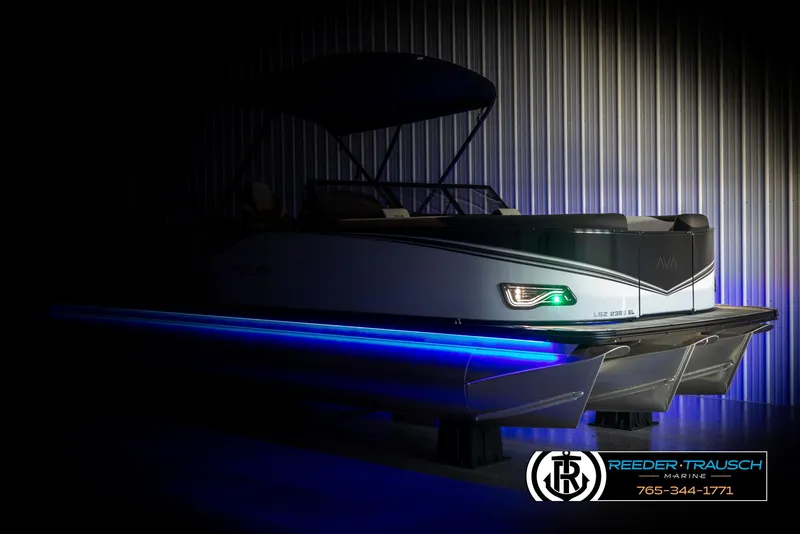 Slide: The Image of 2025 Avalon LSZ EL pontoon boat with blue LED lights in a dimly lit showroom. - 4