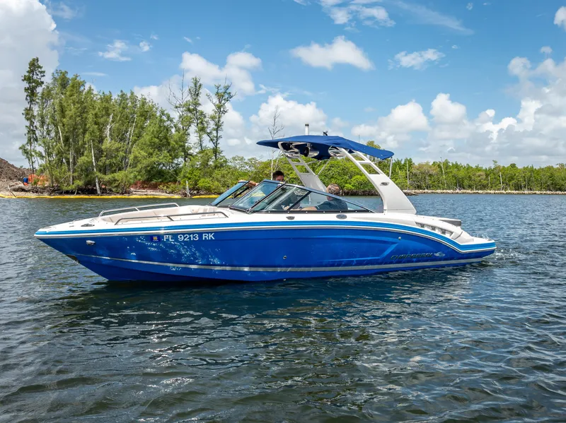 The Image of 2017 Chaparral 227 SSX boat on water, blue hull, sunny day, trees in background. - 0