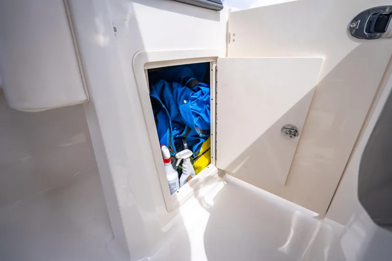 Slide: The Image of Storage compartment on 2017 Chaparral 227 SSX boat with cleaning supplies and blue fabric. - 28