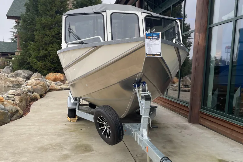 The Image of 2024 Spartan 215 Athens boat on trailer, displayed outdoors near building. - 0