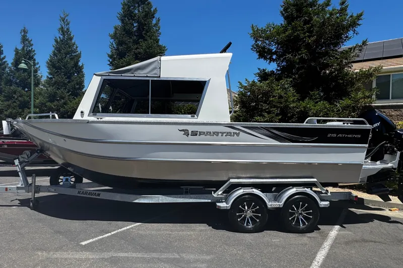 The Image of 2024 Spartan 215 Athens boat on trailer, parked outdoors with trees in background. - 0