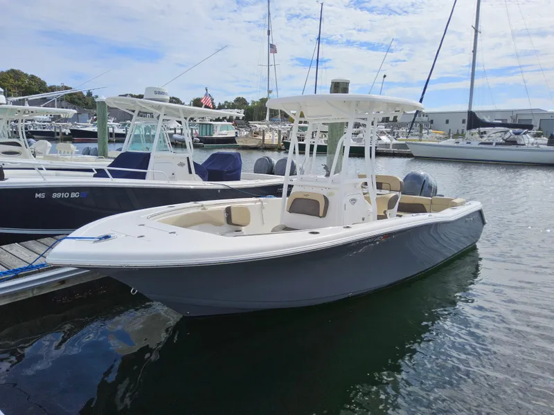 Slide: The Image of 2019 Tidewater 220 LXF boat docked in a marina, surrounded by other vessels. - 2