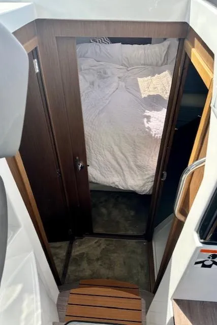 Slide: The Image of 2024 Beneteau Antares 9 cabin interior with cozy bed and wooden accents. - 10