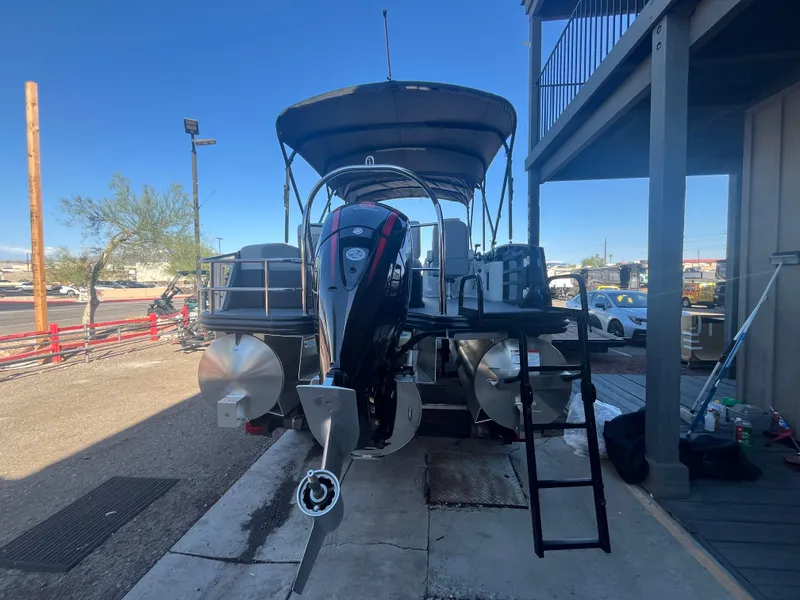 Slide: The Image of 2025 Lowe SS210DHCL pontoon boat with outboard motor, docked under a canopy. - 3