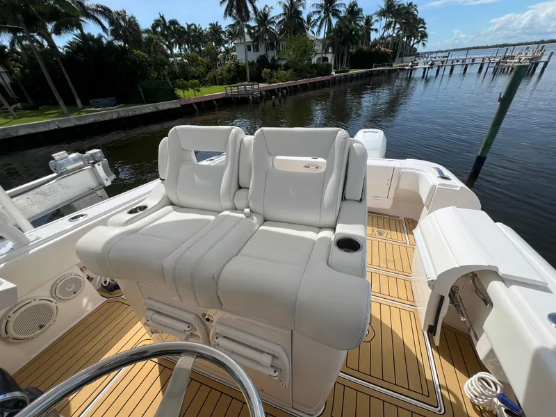 Slide: The Image of 2018 Intrepid 407 Cuddy boat with white seating, docked by palm trees and water. - 10