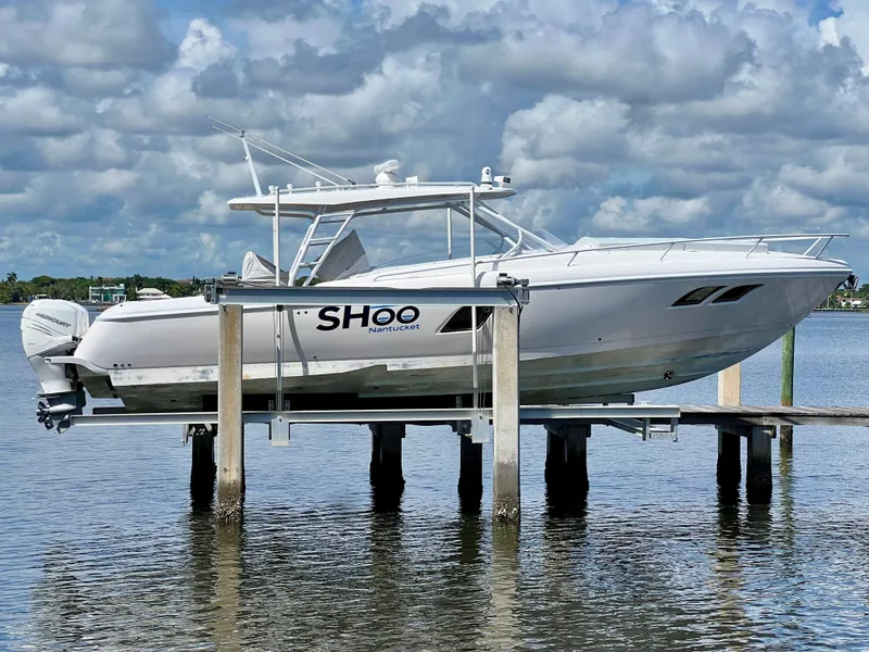Slide: The Image of 2018 Intrepid 407 Cuddy boat on lift, calm water, cloudy sky. - 2