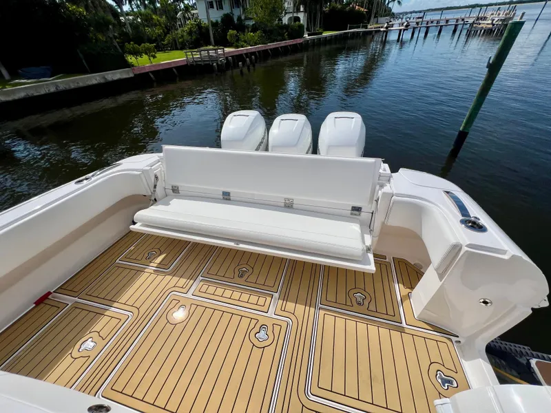 Slide: The Image of 2018 Intrepid 407 Cuddy boat with teak deck and triple engines, docked by the water. - 9