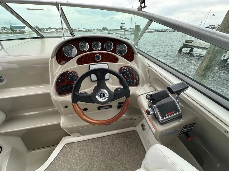 Slide: The Image of 2008 Sea Ray 280 Sundancer helm with wood-accented steering wheel and control panel, docked at marina. - 6