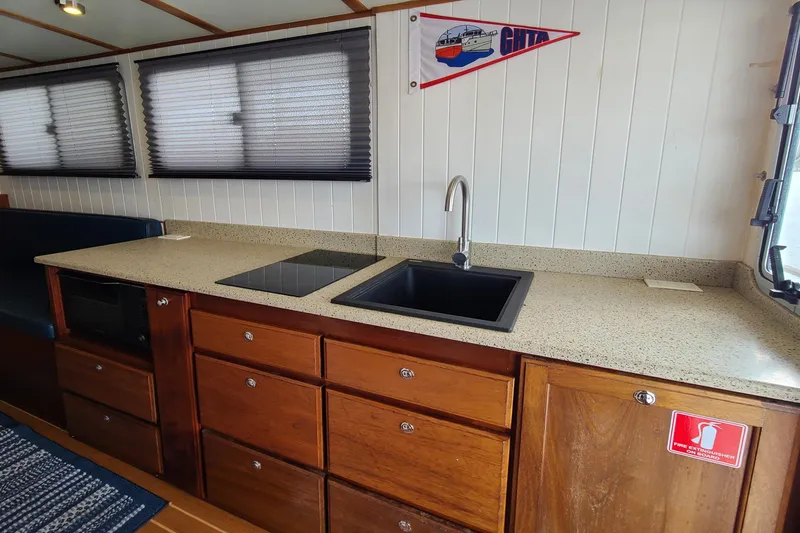 Slide: The Image of 2018 Great Harbour TT35 boat interior kitchen with sink, stovetop, and wooden cabinetry. - 7