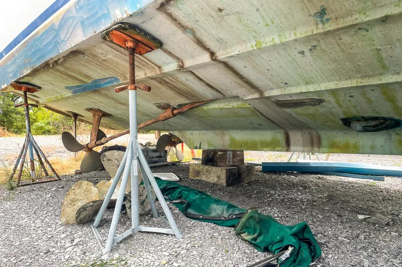 Slide: The Image of 1978 Bertram 46 Convertible boat hull on stands, showing propellers and keel. - 10