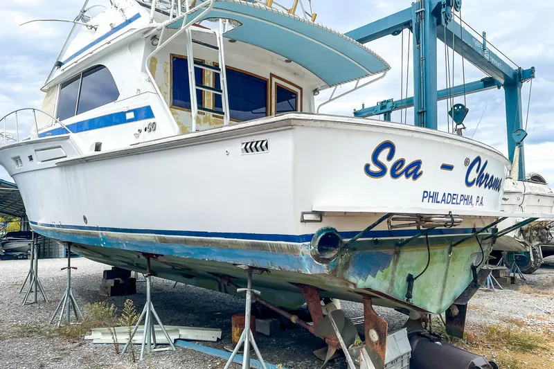 Slide: The Image of 1978 Bertram 46 Convertible boat on stands, named "Sea-Chaser," in a boatyard. - 13