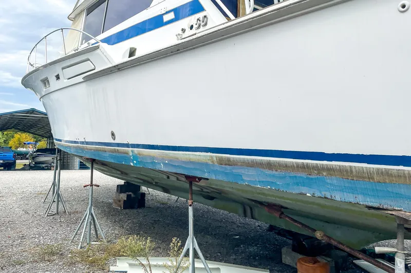 Slide: The Image of 1978 Bertram 46 Convertible boat on stands, undergoing maintenance in a gravel yard. - 15