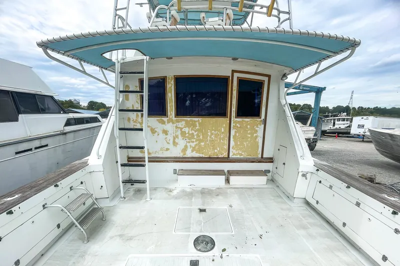 Slide: The Image of 1978 Bertram 46 Convertible boat with weathered exterior, docked at a marina. - 23
