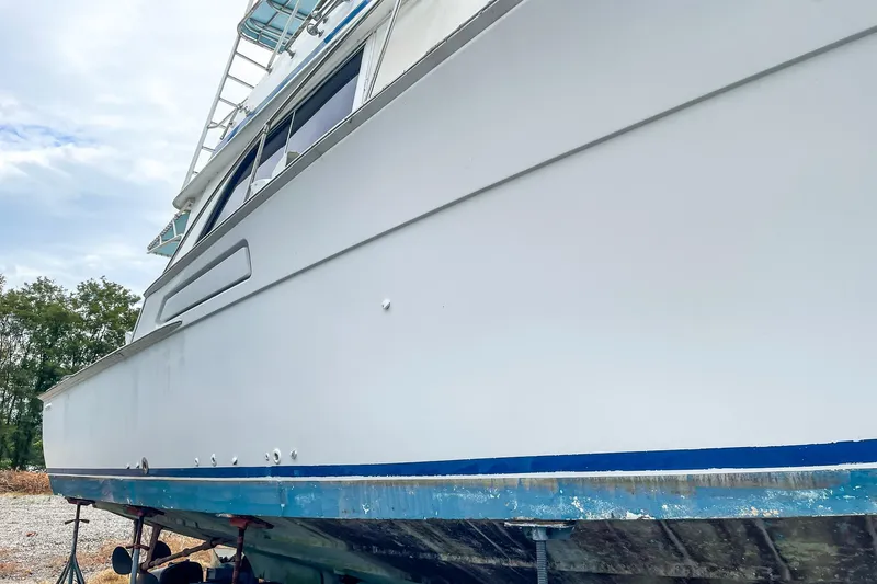 Slide: The Image of 1978 Bertram 46 Convertible boat on land, side view, with blue trim. - 9