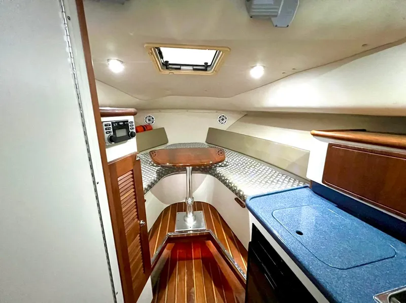 Slide: The Image of 2005 Pursuit 3070 WA EXPRESS cabin interior with wood flooring and compact kitchenette. - 13