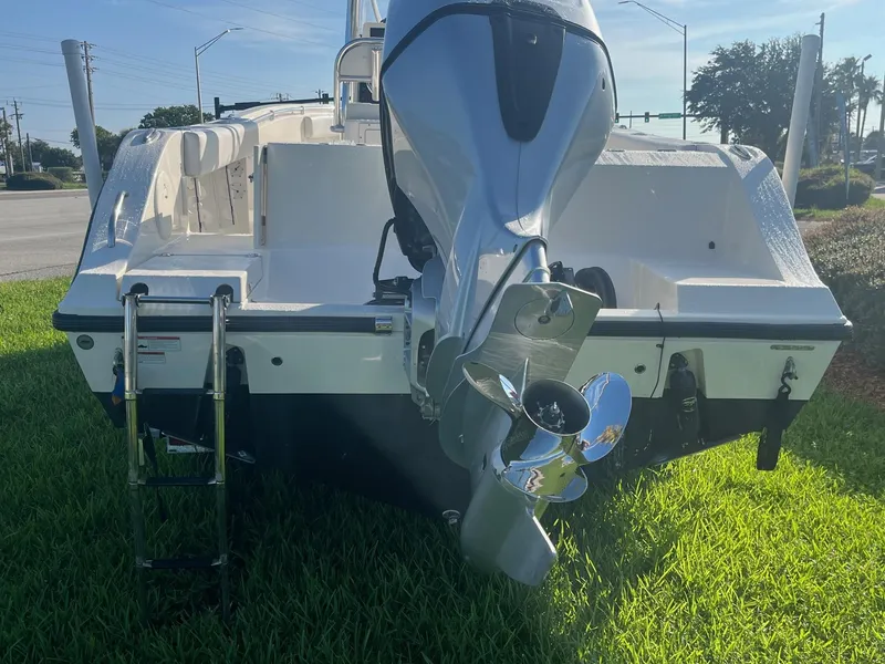 Slide: The Image of 2022 Cobia 237 Center Console boat with outboard motor and ladder on grass. - 2