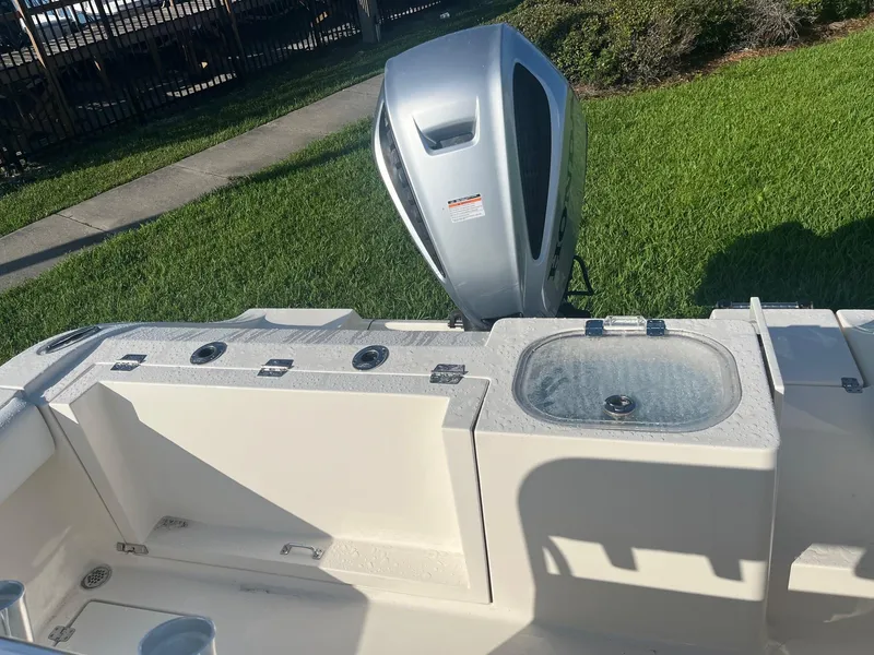 Slide: The Image of 2022 Cobia 237 Center Console boat with outboard motor and livewell on grassy area. - 7