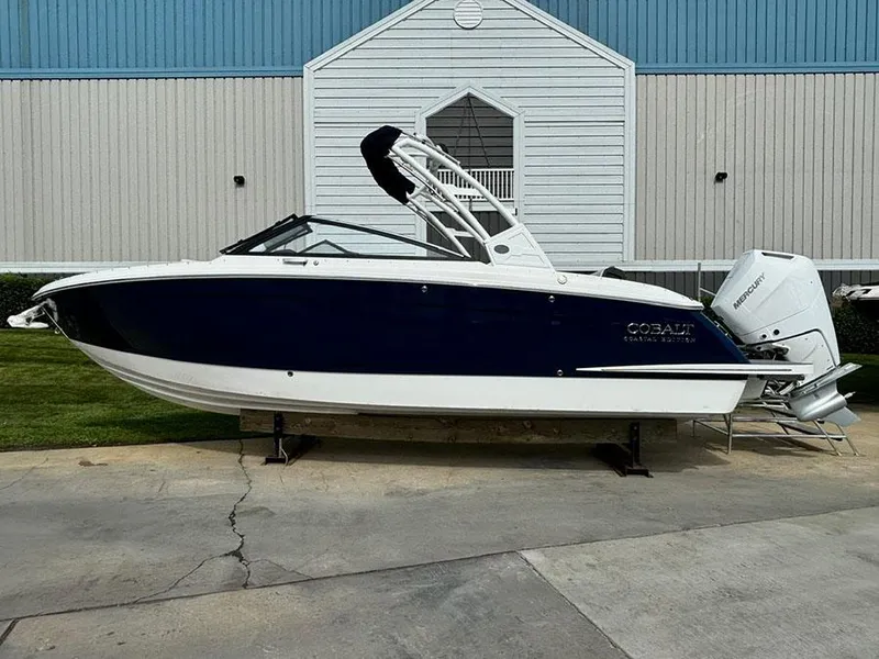 The Image of 2025 Cobalt R6 Outboard boat, blue and white, displayed outdoors near a building. - 2