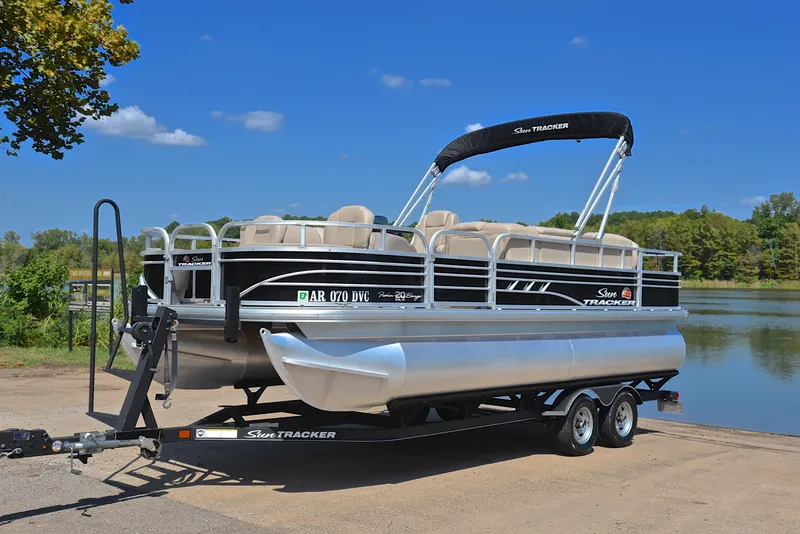 Slide: The Image of 2021 Sun Tracker Fishin Barge 20 DLX pontoon boat on trailer by a lake. - 10